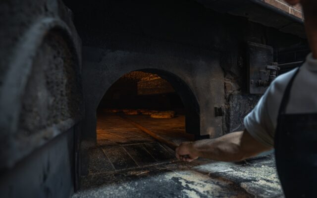 Chef placing pizza into a brick oven