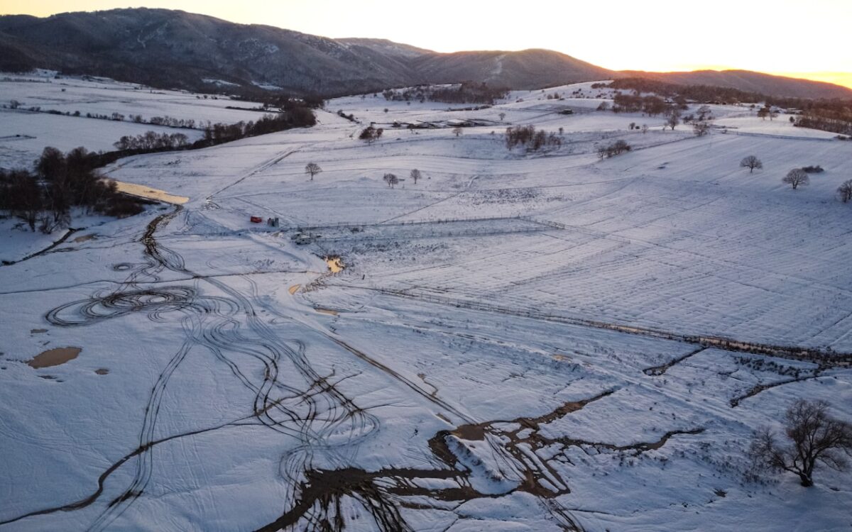 Snowy landscape with rolling hills at sunset