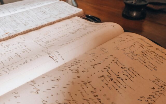 Open old books with handwritten text on a wooden table.