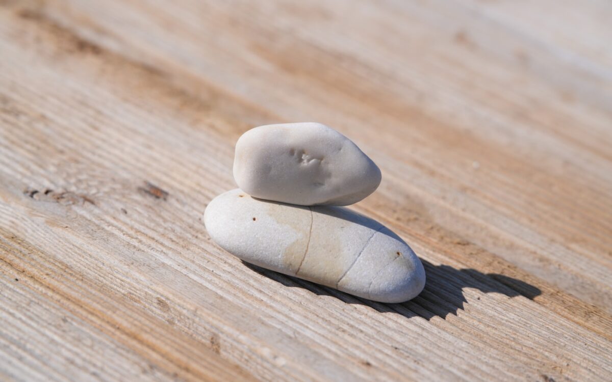 Two smooth stones stacked on weathered wood