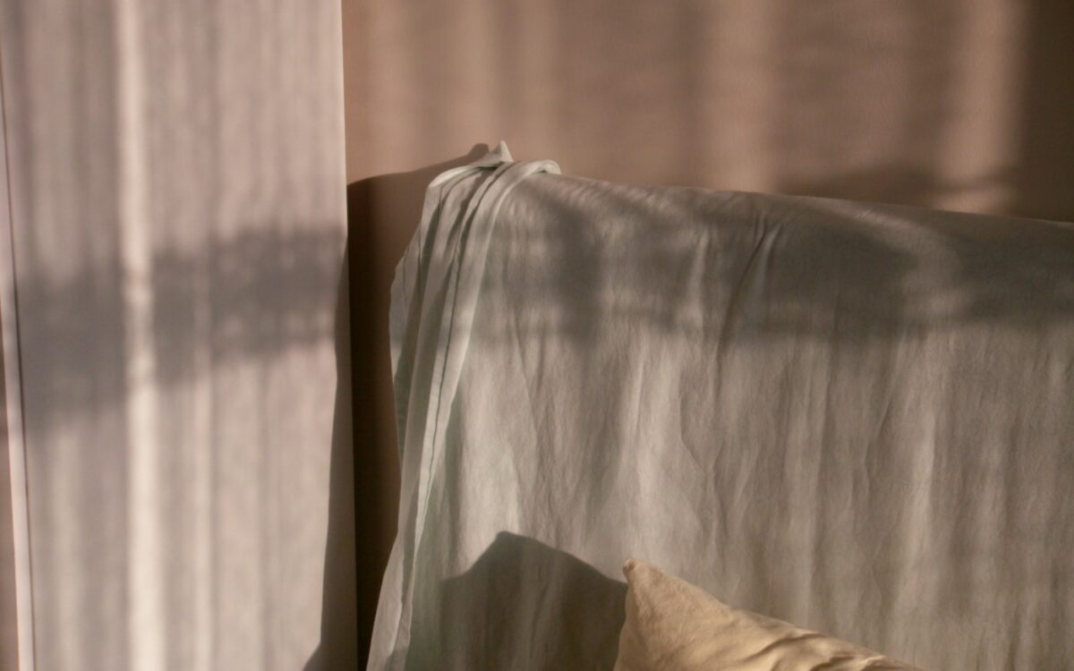 Sunlight casts shadows on a draped sofa.
