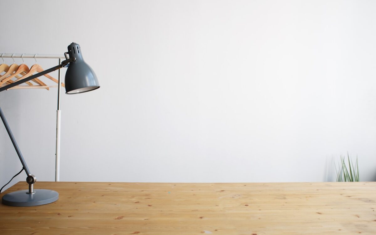 gray balanced-arm lamp on brown wooden table