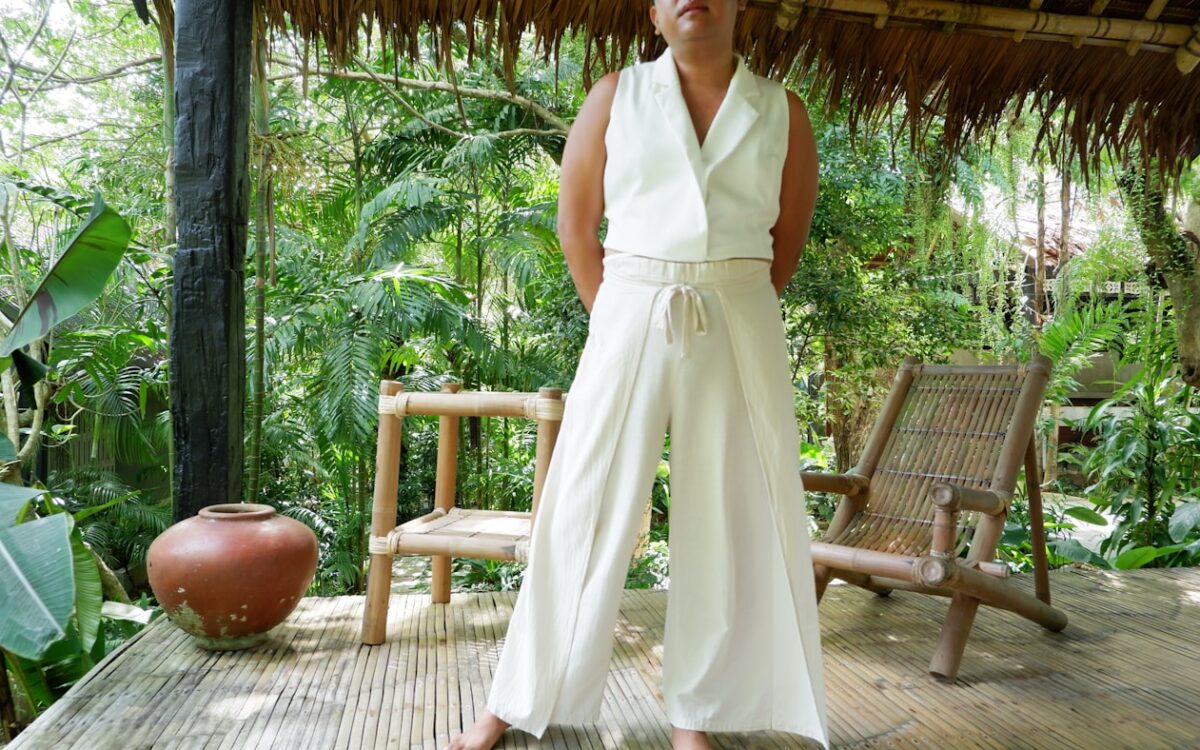 Woman in white outfit standing on a wooden porch.