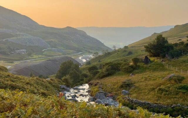 Mountain valley with a stream at sunset.