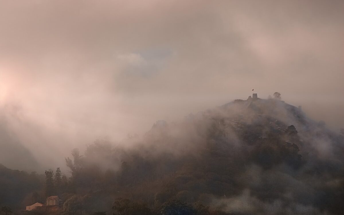 Misty mountain peak with clouds and sunlight.