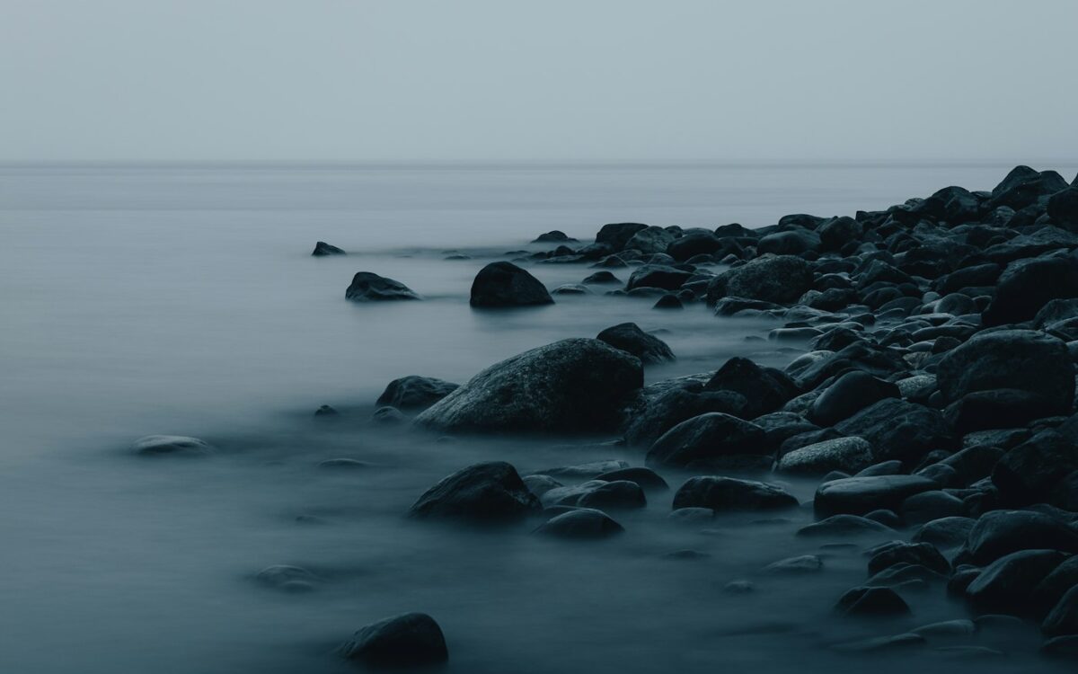 black rocks on body of water during daytime