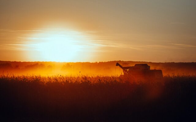a tractor in a field with the sun setting in the background