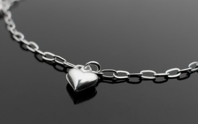 a silver heart necklace on a black surface