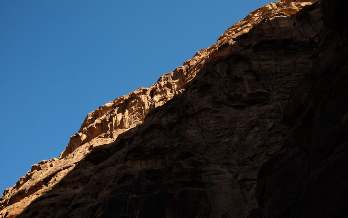 Sunlight illuminates rocky cliff face against blue sky