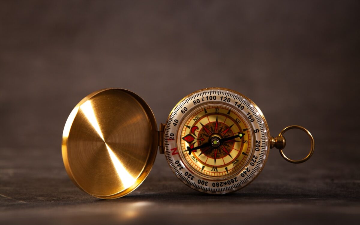 Antique brass compass with open lid on dark surface