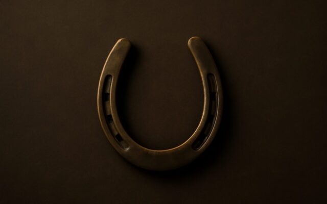 Brass horseshoe against a dark background, illustrating the 1930 Metal Horse (Geng Wu) zodiac year