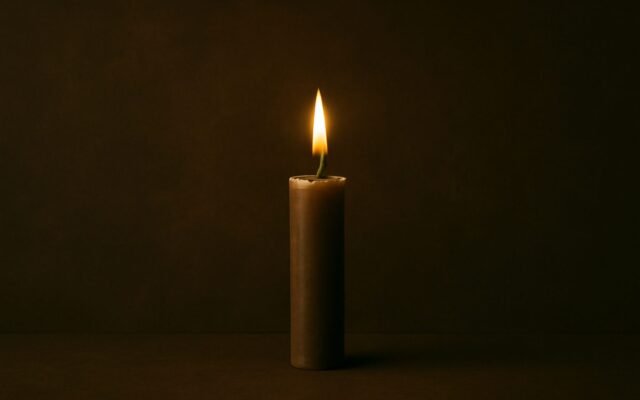 Single candle flame in the dark, reflecting the 1977 Fire Snake (Ding Si) Chinese zodiac year