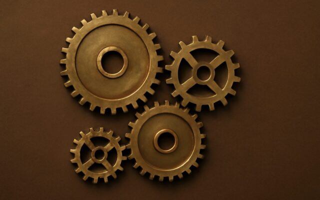 Four brass gears on a brown background, illustrating the 1980 Metal Monkey (Geng Shen) zodiac year