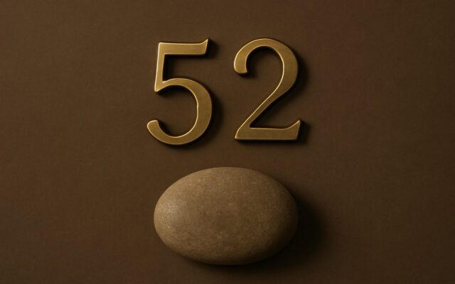 Brass house numerals above a smooth pebble on a brown wall, illustrating the meaning and use of numbers in feng shui