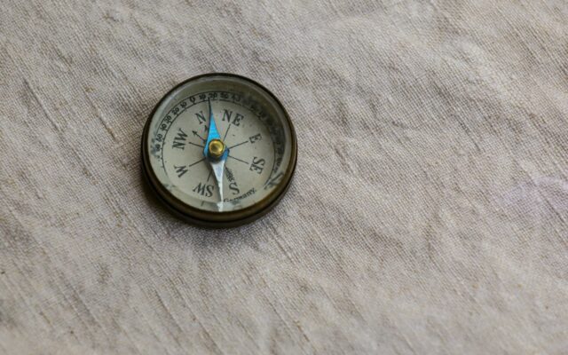 Small brass compass resting on textured white paper, for the 2027 Flying Stars chart of the Fire Goat year