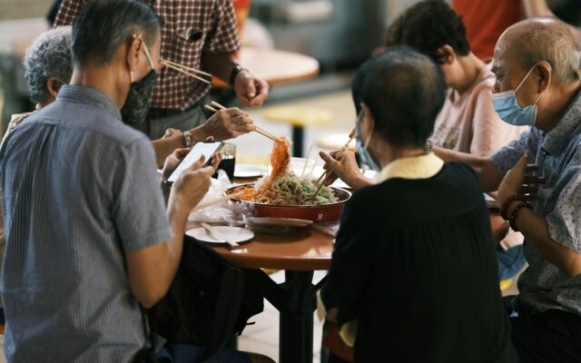 Family tossing yusheng together at a Chinese New Year meal